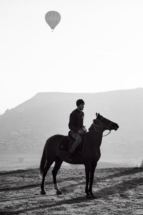 Hot Air Balloon Flying over Man Riding on Horse