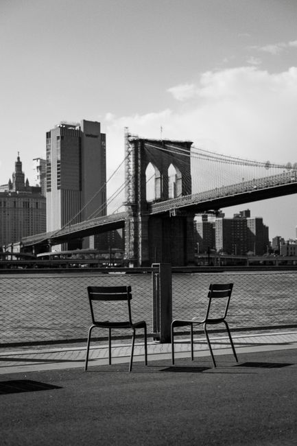 Stunning cityscape of Brooklyn Bridge with empty chairs, ideal for urban themes.