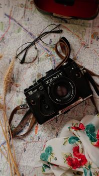Zenit camera placed on a map with floral fabric and glasses, capturing nostalgia and travel vibes.