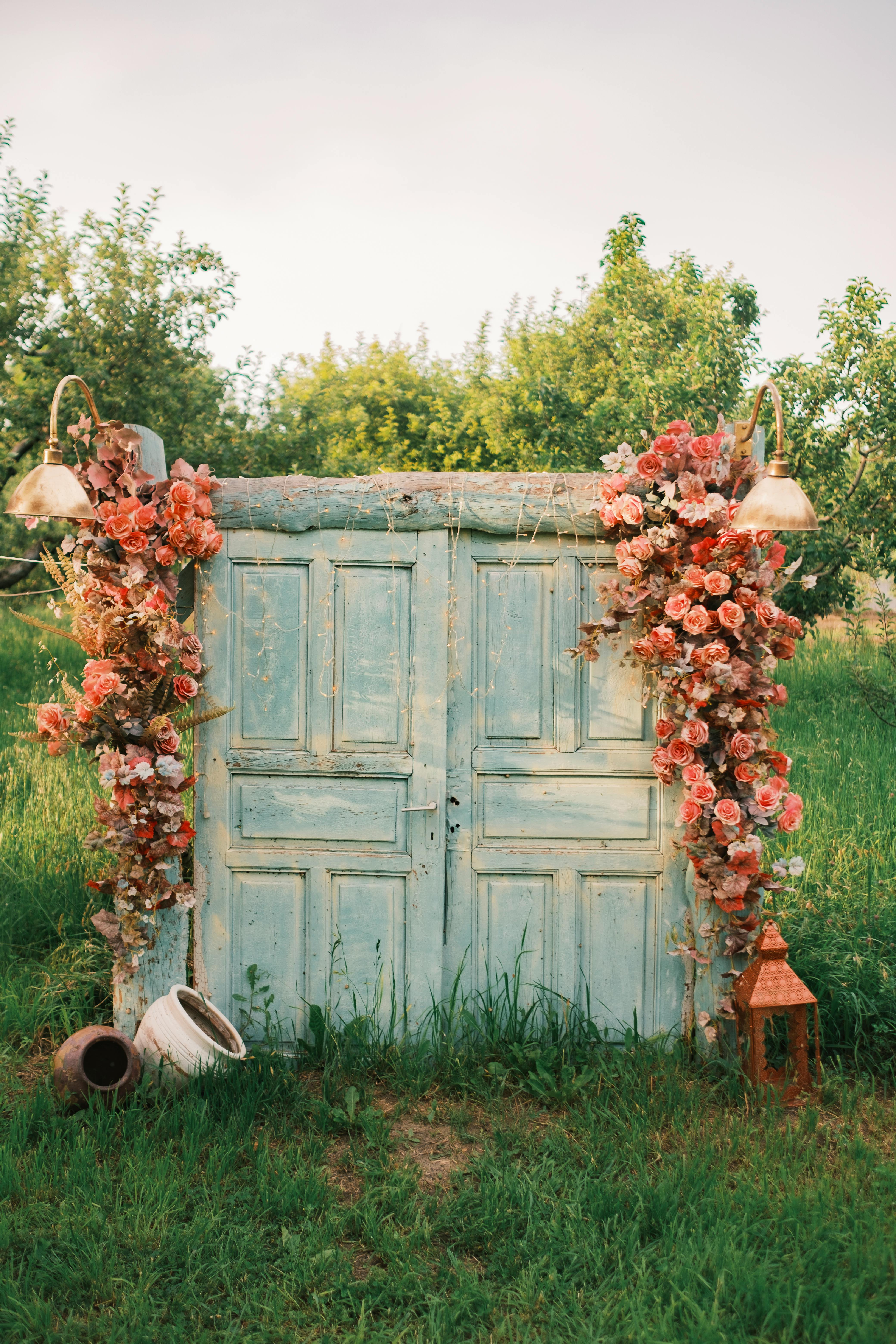A rustic door decorated with flowers in a lush summer orchard, creating a charming countryside scene.