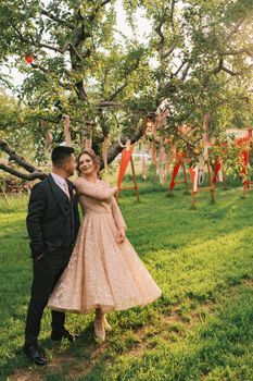 A loving couple poses in a lush green orchard during a rustic outdoor wedding photoshoot.