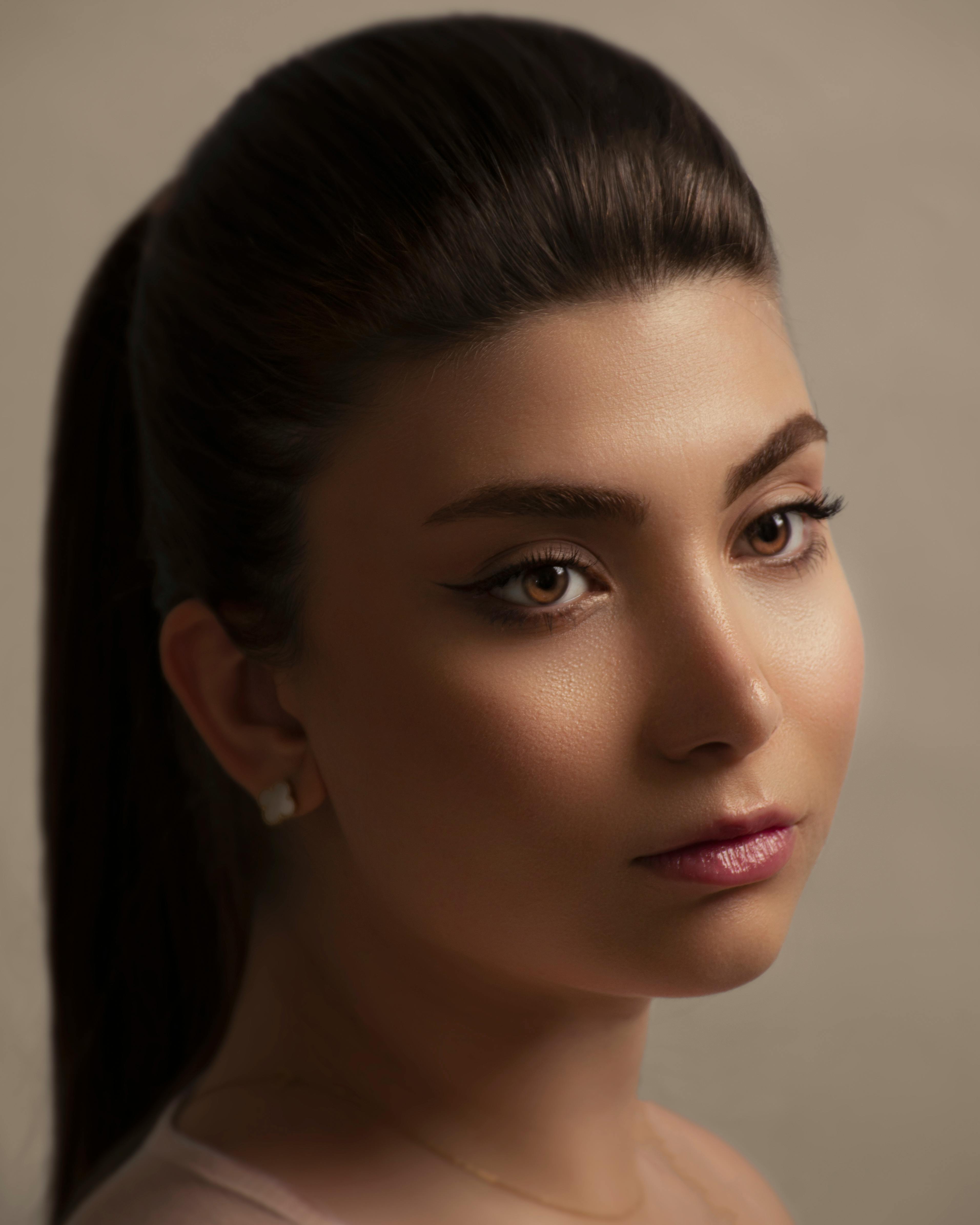 Studio portrait of a young woman with serene expression and professional makeup.