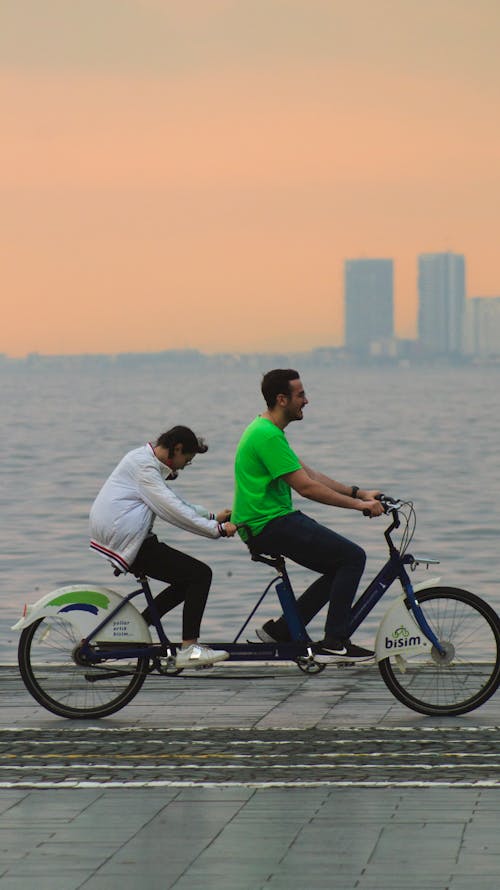 Couple Riding Tandem Bike on Promenade at Sunset