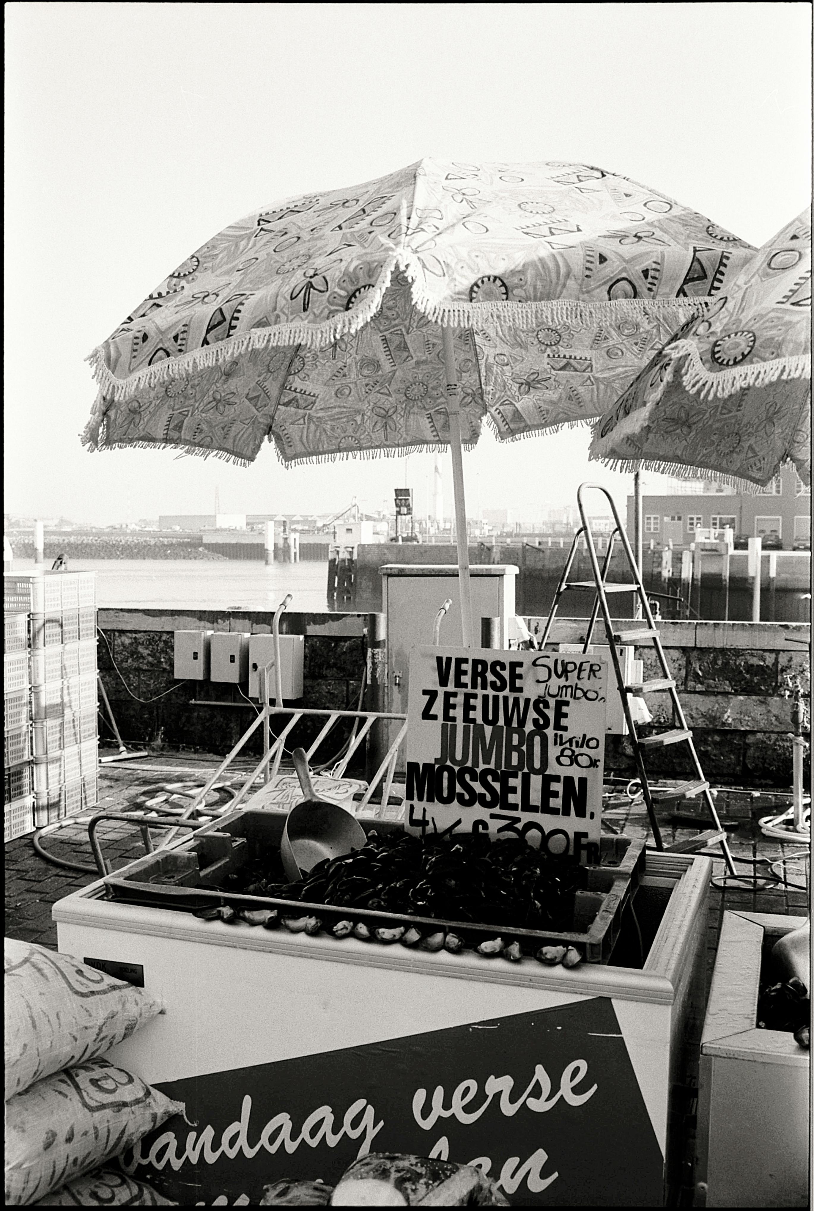 Monochrome image of a street food stall selling jumbo mussels by the waterfront.
