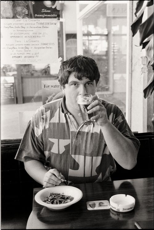 Free A man drinks beer and eats in an indoor restaurant setting, captured in monochrome. Stock Photo