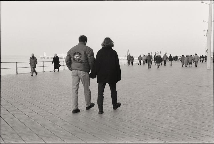 Couple In Jackets Walking Together On Promenade