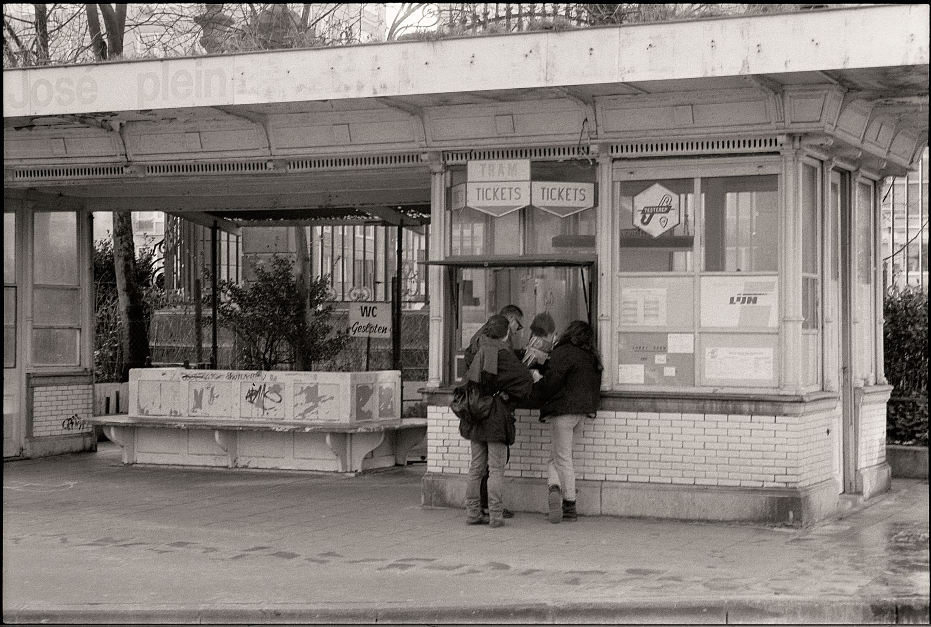 Vintage tram ticket booth with people buying tickets in black and white.