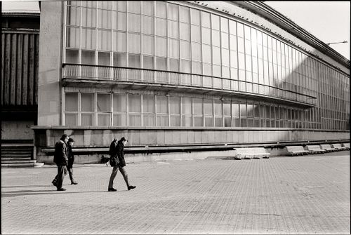 Free Monochrome image of people walking near a modern architectural building. Stock Photo