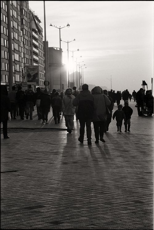Free Black and white photo of a busy city street with people walking at sunset. Stock Photo