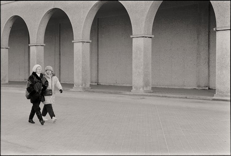 Women In Winter Clothes Walking Across Plaza Next To Arcades