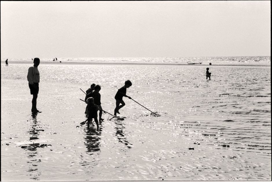 Silhouetten van kinderen die op een ondiep strand spelen
