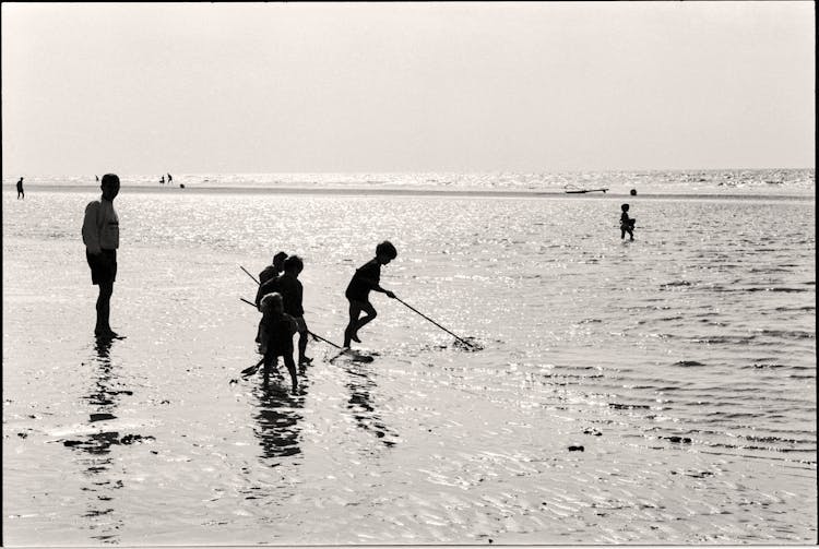 Man And Kids Standing In Shallow Water