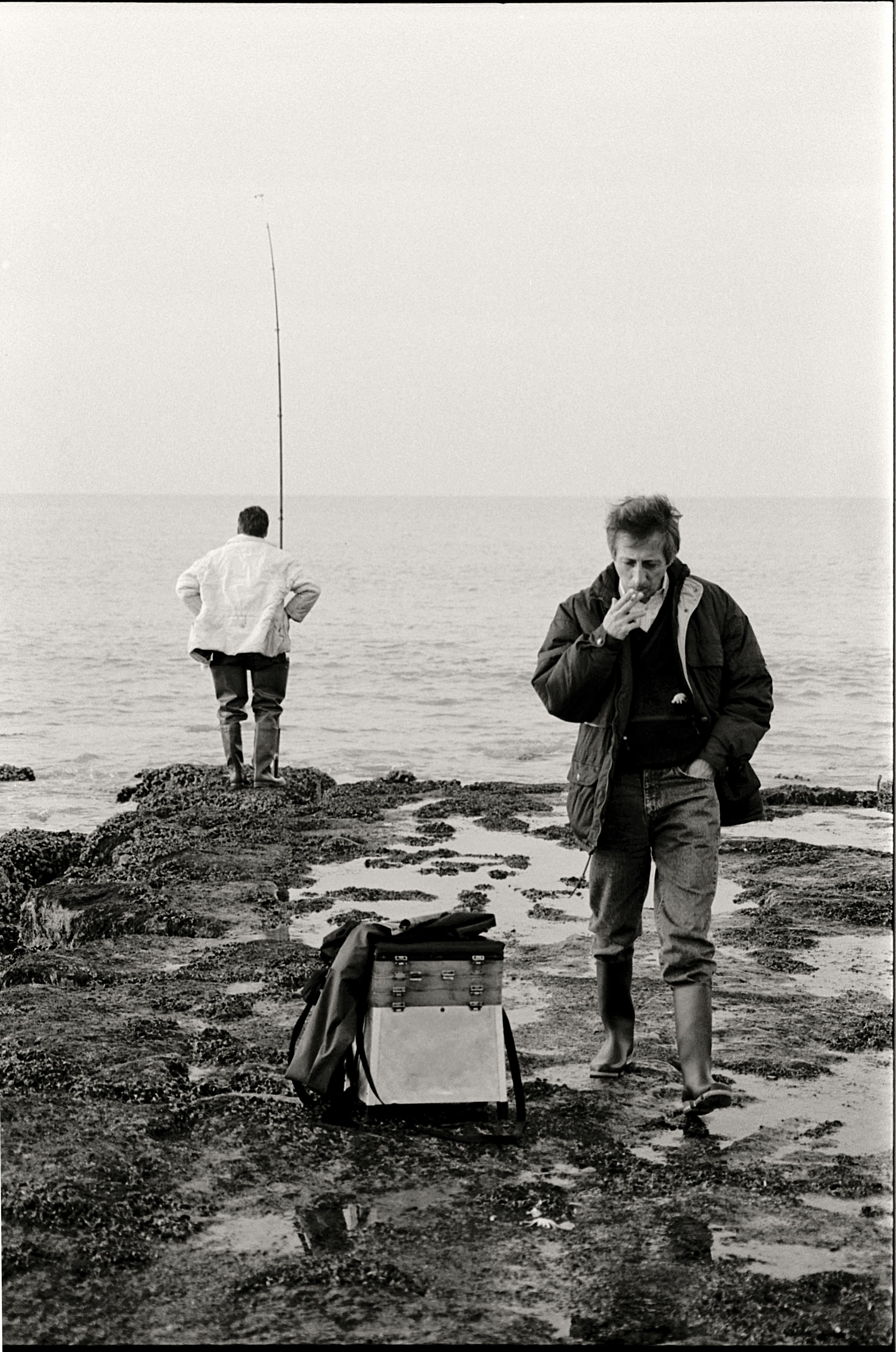 fishermen standing on shore in black and white