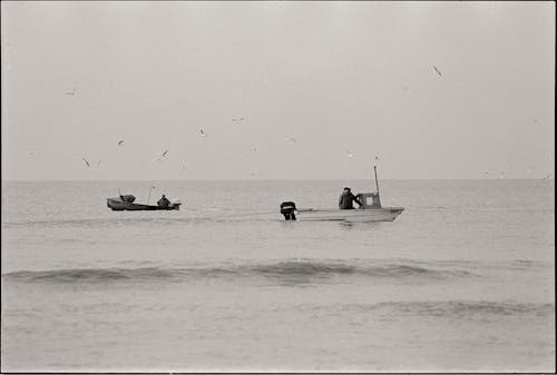 Black and White Picture of Men in Boats on the Sea 