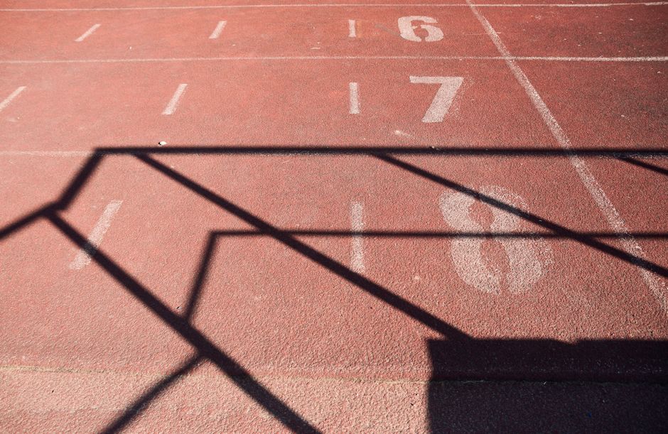 A sunlit athletics track marked with numbers and dynamic shadows, perfect for sports themes.