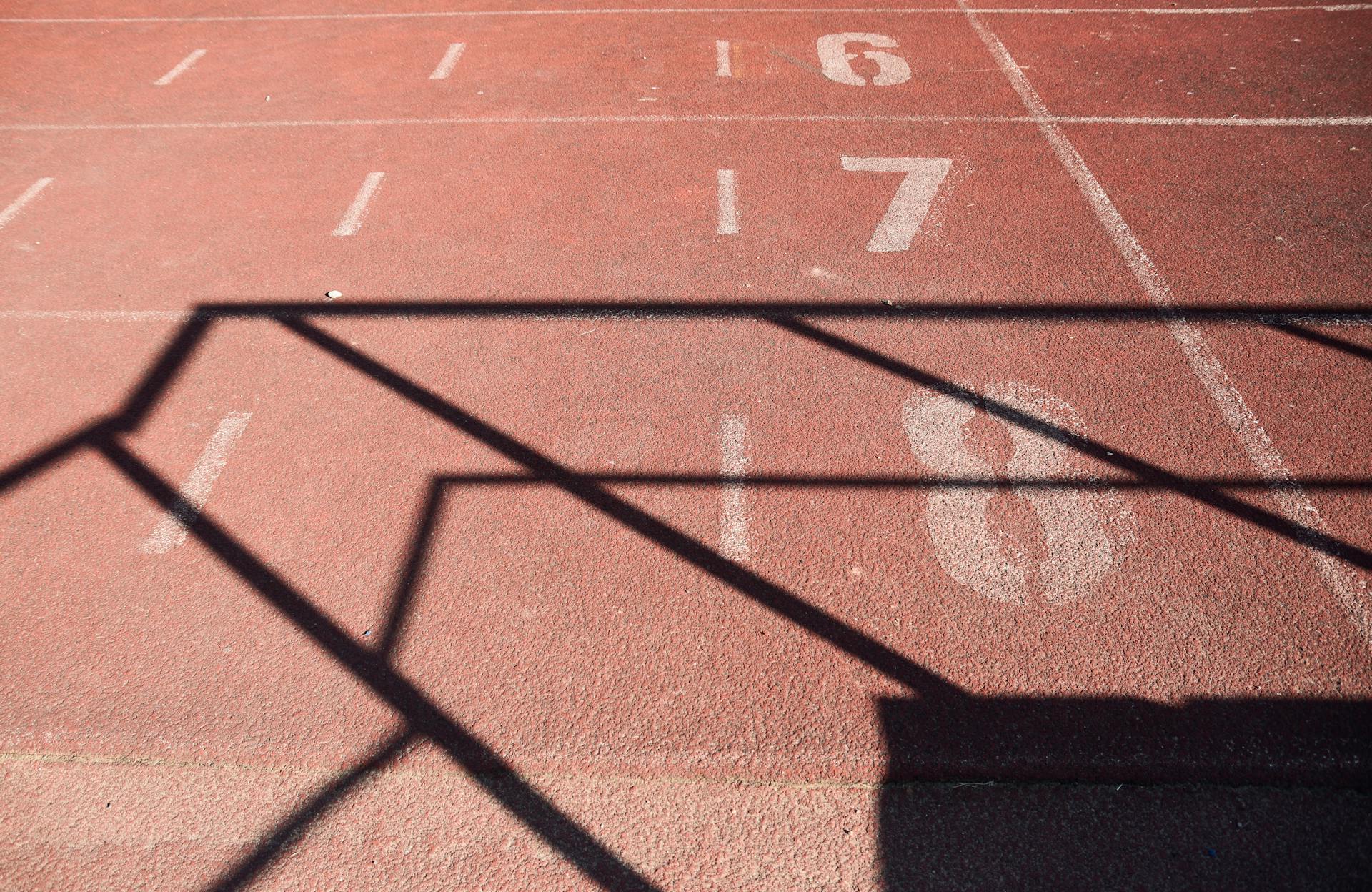 A sunlit athletics track marked with numbers and dynamic shadows, perfect for sports themes.