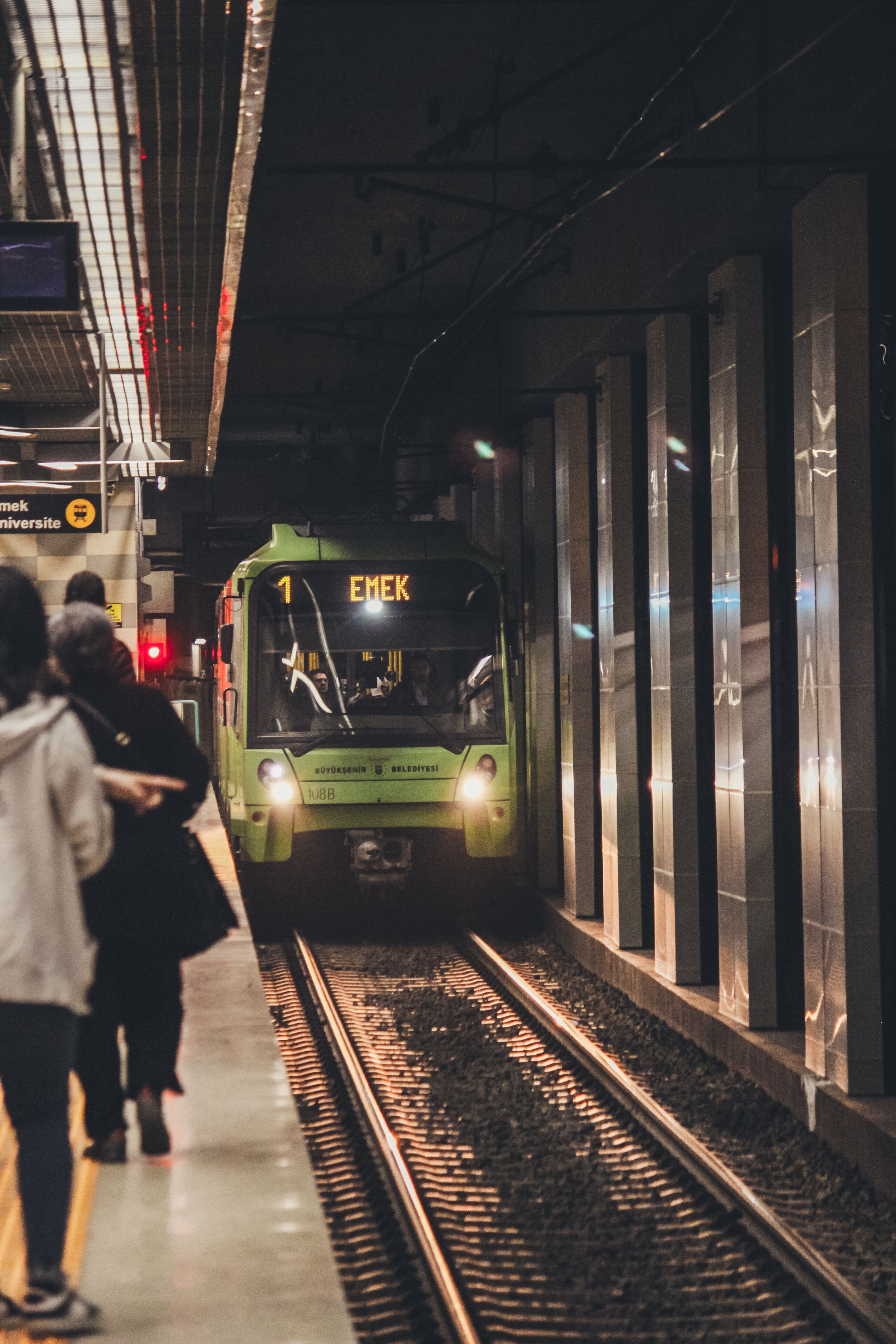 A dark train platform with a metro arriving at Emek station in Bursa, Turkey.