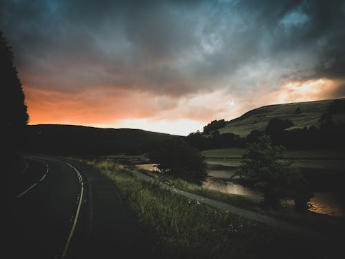 Free Landscape Photography of Road Beside Body of Water at Golden Hour Stock Photo