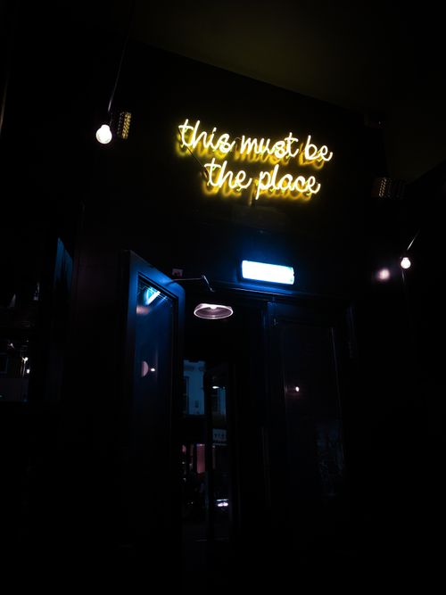 Free Dark setting with illuminated neon sign reading 'this must be the place'. Stock Photo