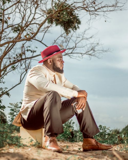 Free Fashionable man with a beard and red hat sitting outdoors, exuding style and elegance. Stock Photo