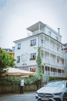 Elegantly designed white villa in urban setting with lush greenery, capturing serene city charm.