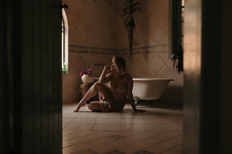 Smiling Woman Sitting On Floor In Bathroom