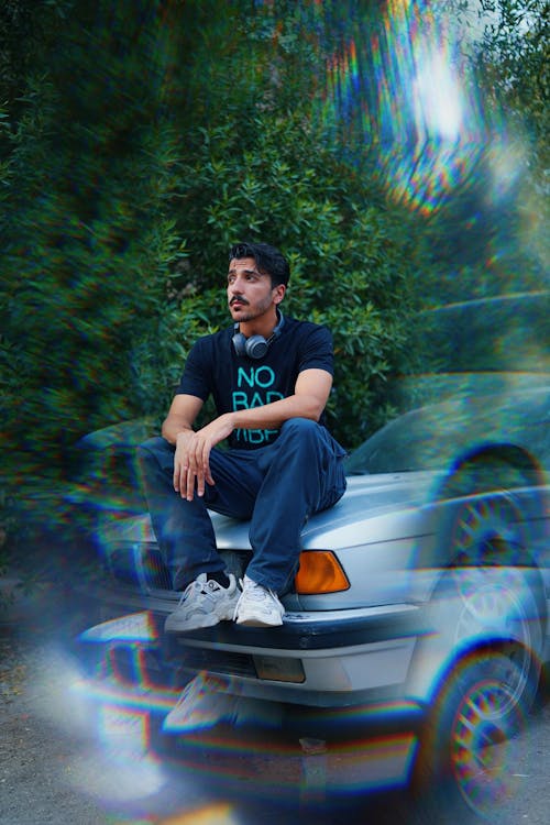 Man with Mustache Sitting on Car Bonnet