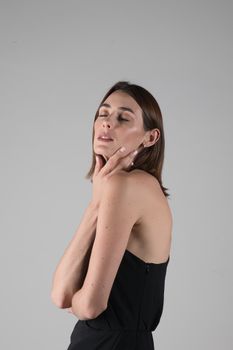 Graceful portrait of a woman in a black dress against a gray background.