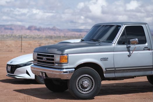 Classic Ford truck and modern car in a serene desert backdrop on a sunny day.