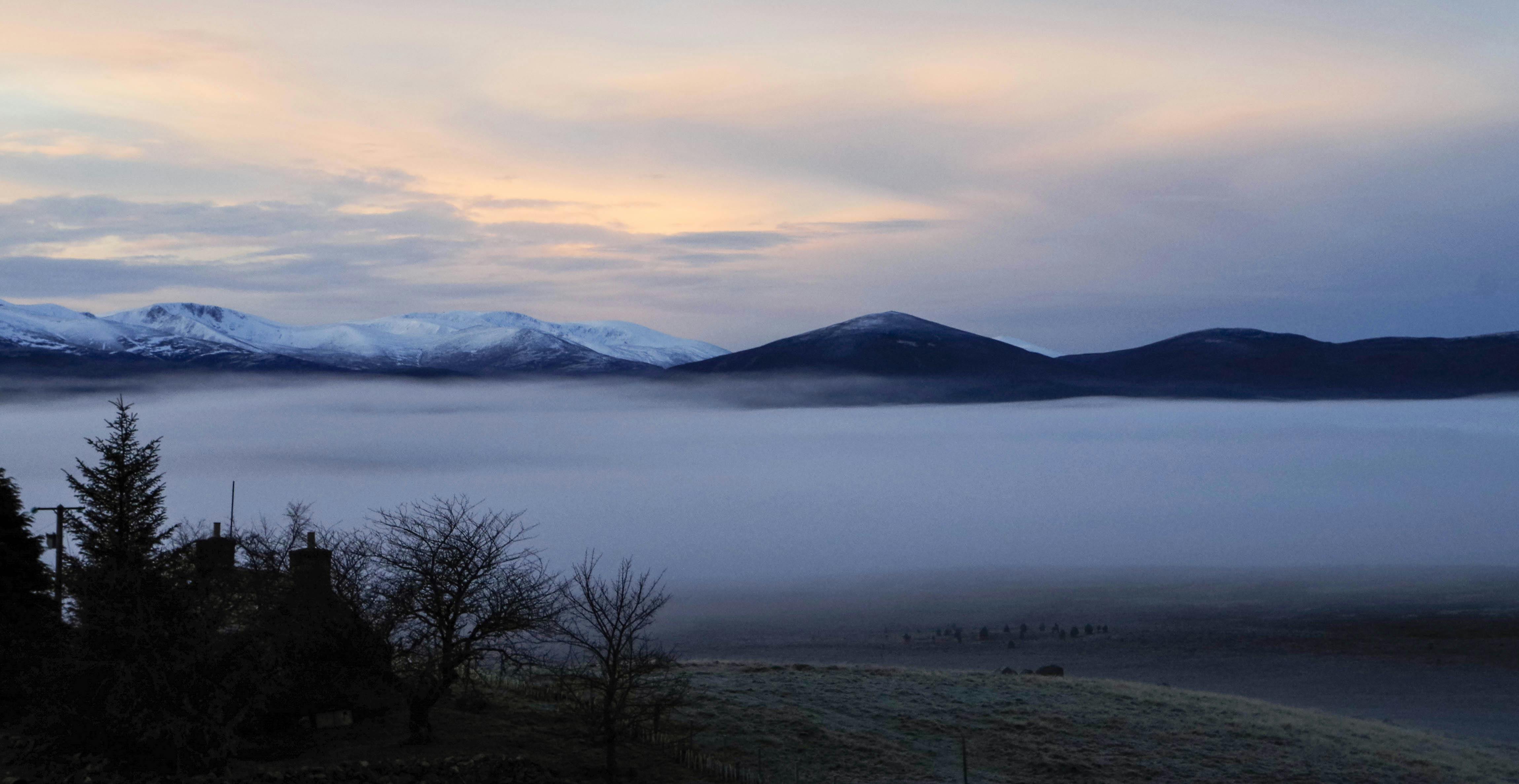 冬日宁静的景象，是日落时分白雪皑皑的群山与浓雾