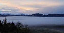 冬日宁静的景象，是日落时分白雪皑皑的群山与浓雾