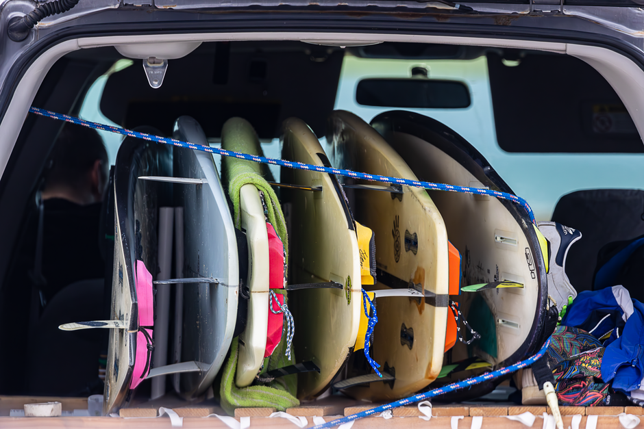 Surfboards stacked in car trunk, ready for a beach surfing adventure.