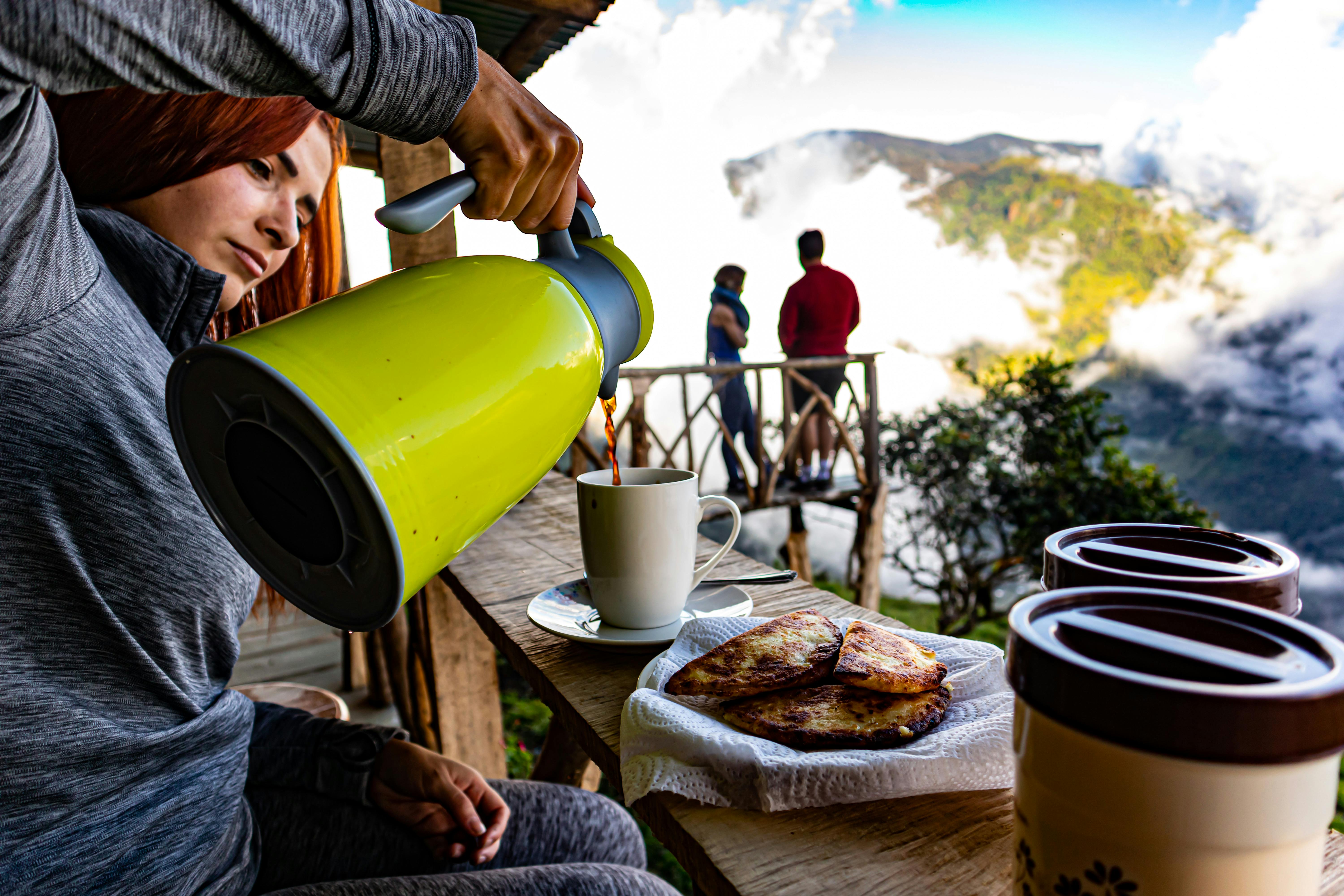 A woman pours coffee on a terrace in San José, Costa Rica, with stunning mountain views.