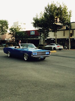 Blue vintage convertible cruising on city street, evoking nostalgia and retro vibes.