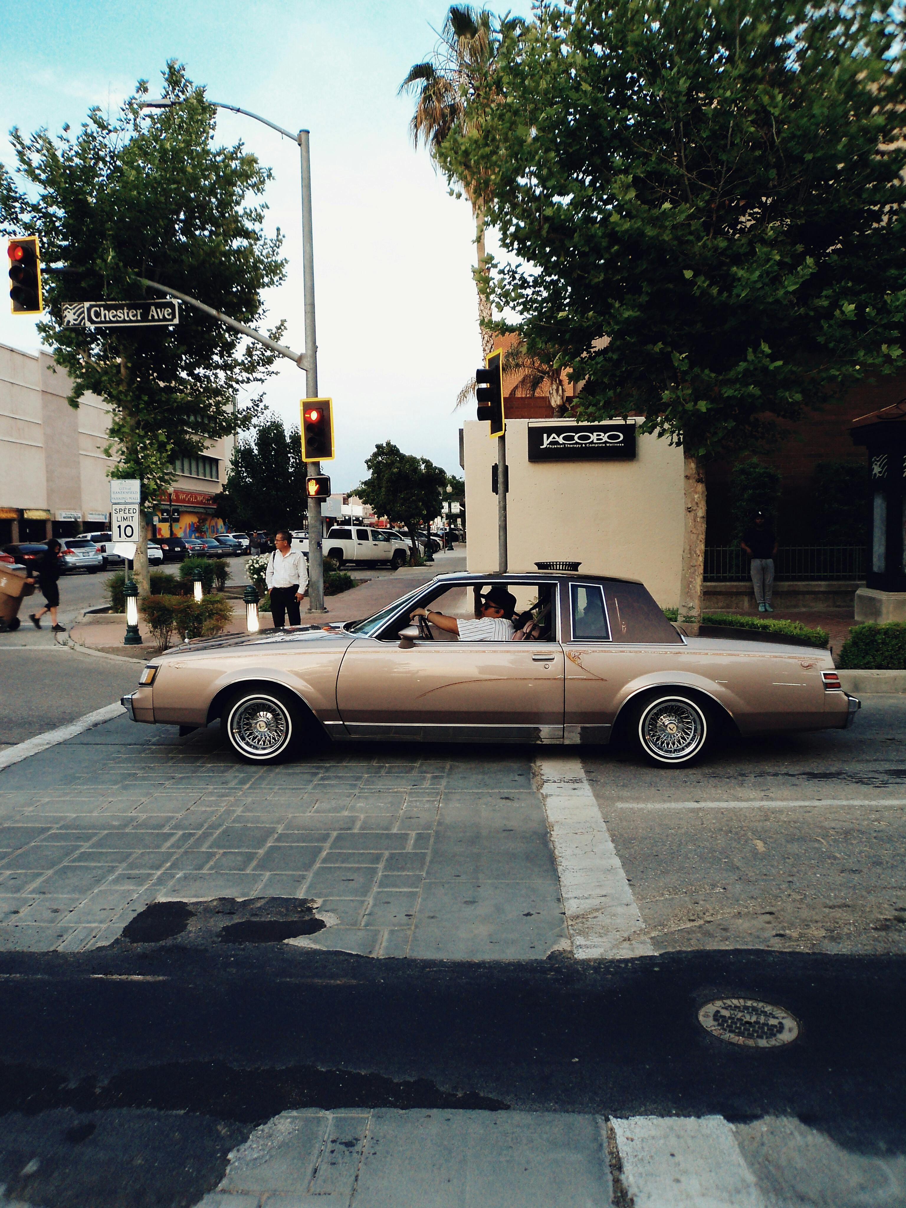 Retro Buick Regal cruising through a city intersection, evoking vintage urban life.