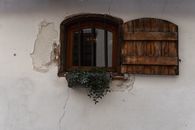 Charming old window with rustic wooden shutters and ivy in urban Riga, Latvia.