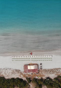Stunning aerial shot of Porto Pino beach with deckchairs and umbrellas on a sunny day.