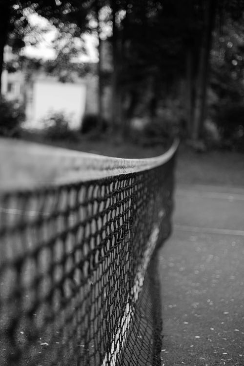 Free A close-up view of a tennis net in black and white, highlighting texture and depth on the court. Stock Photo