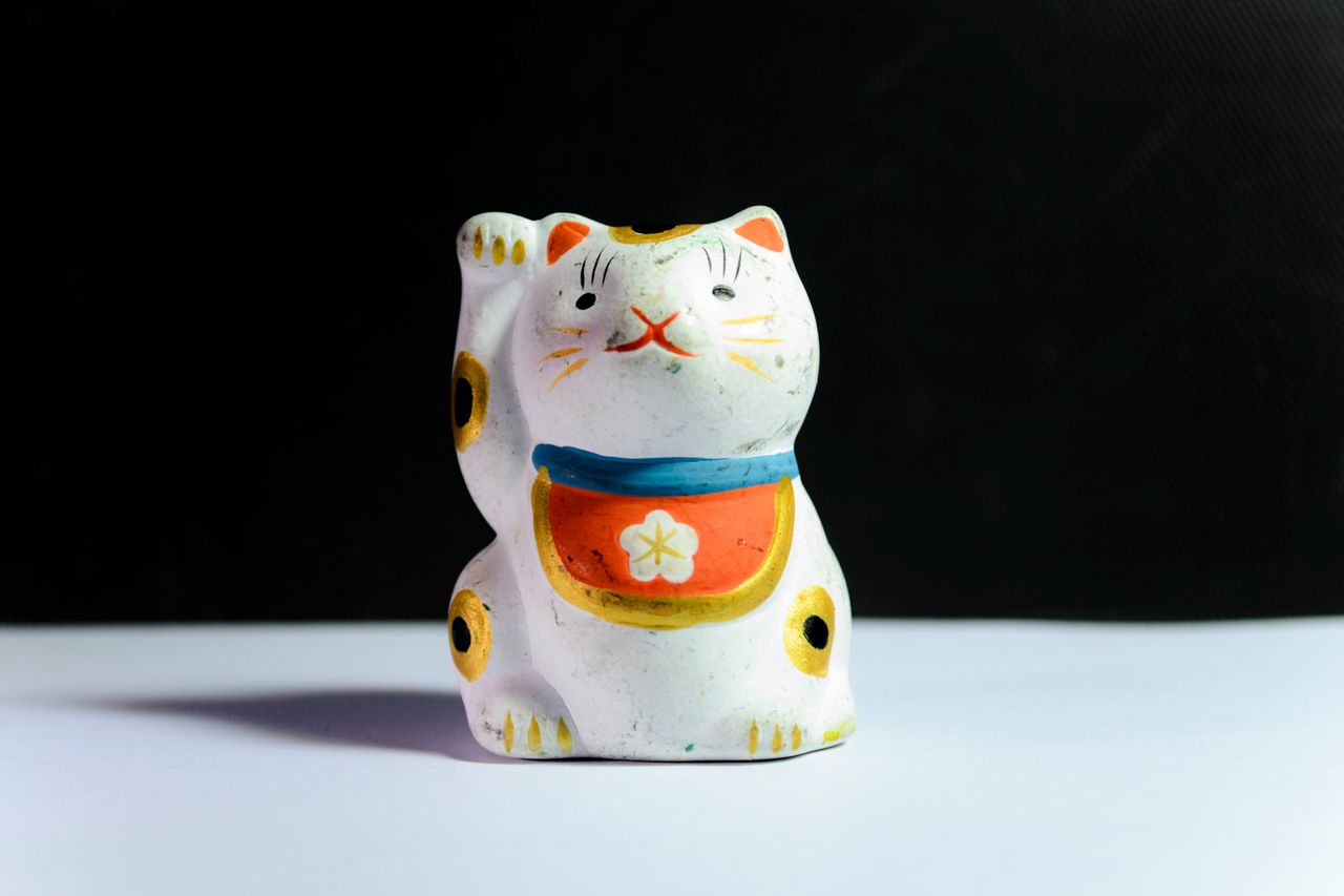 a traditional maneki neko figurine symbolizing luck and prosperity cap