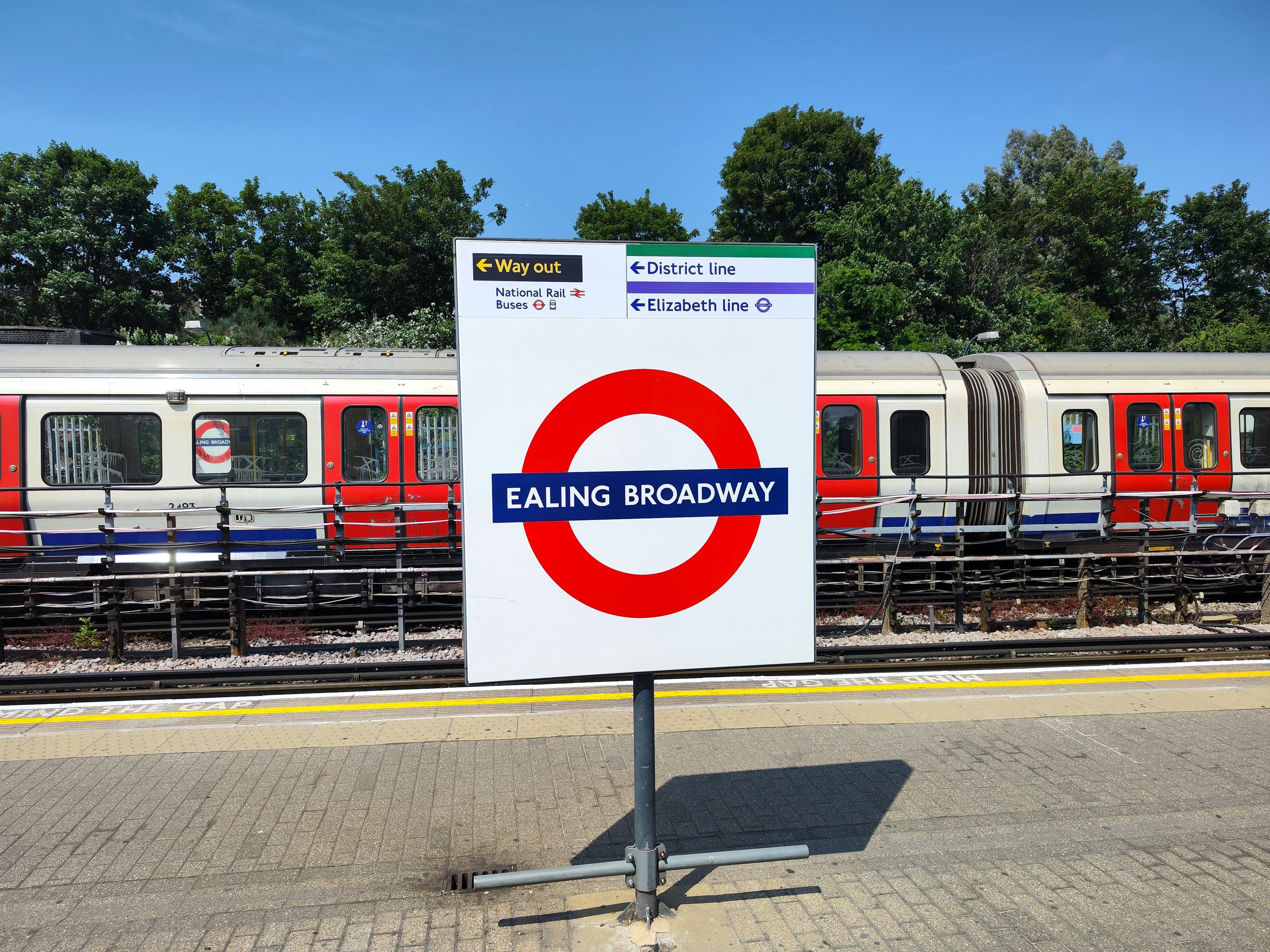 Ealing Broadway sign at a London Underground platform on a sunny day.