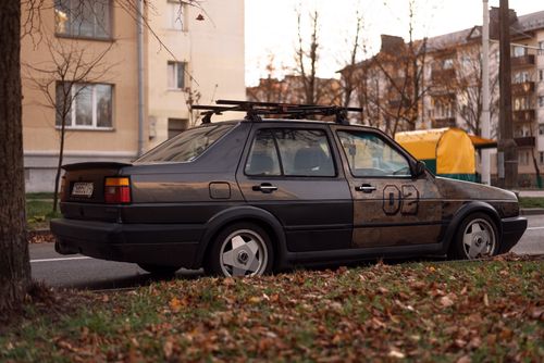 Free A vintage Volkswagen Jetta parked on a city street covered with autumn leaves, reflecting urban decay. Stock Photo