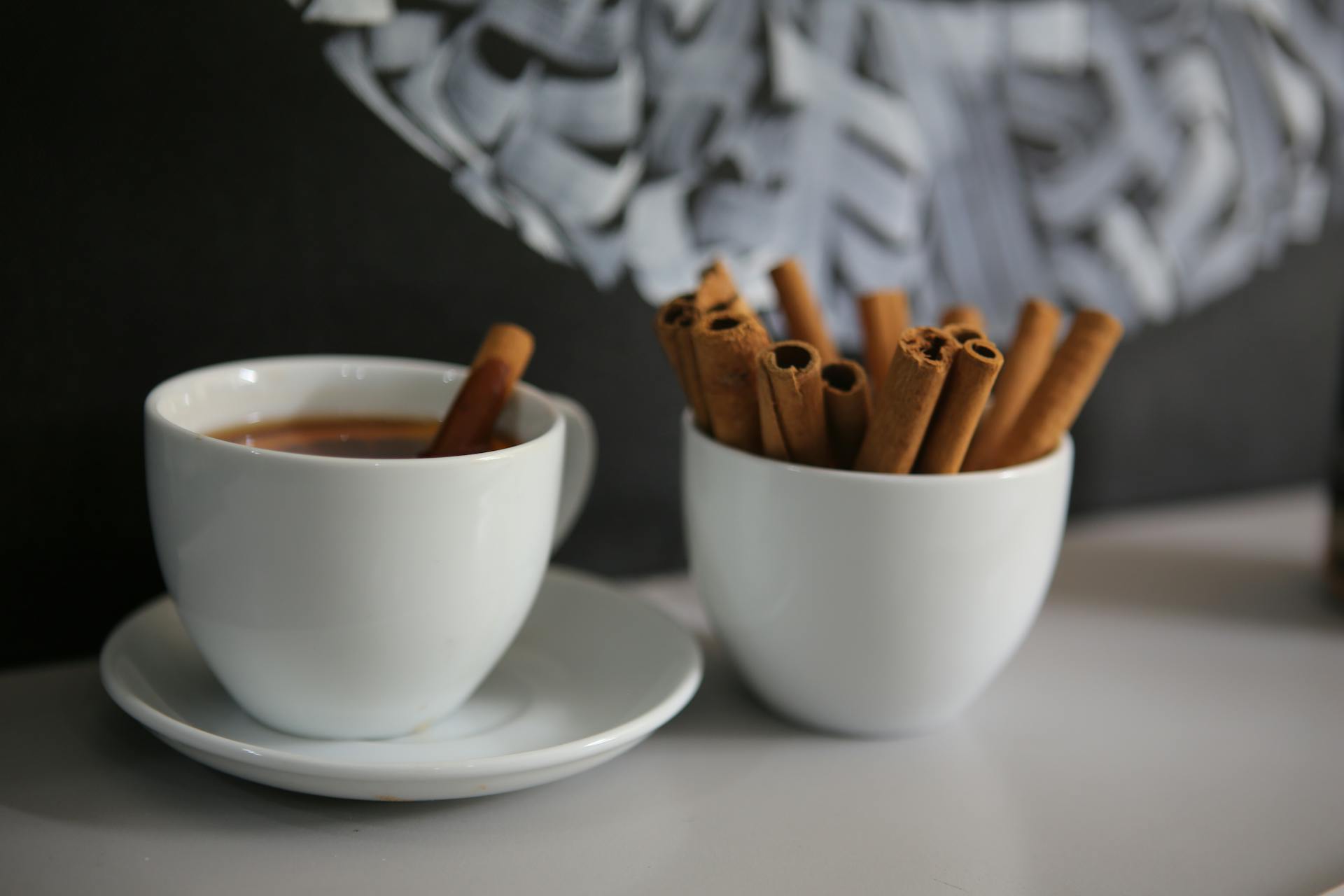 A cozy cup of coffee with cinnamon sticks on a table, creating a warm atmosphere.