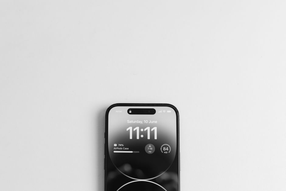 Fitbit Charge 6 vs Garmin Vivosmart 5: Budget Fitness Tracker Showdown (2024) Top view of a smartphone displaying the time 11:11, on a minimalist white background.