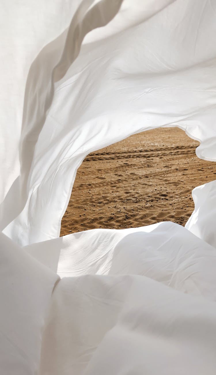 Tire Tracks On Sand Seen Through Hole In White Fabric