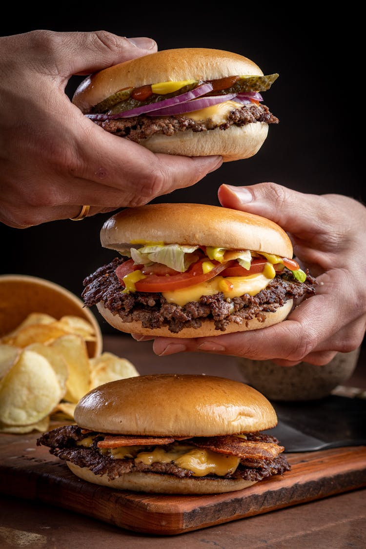 Hands Holding Cheeseburgers