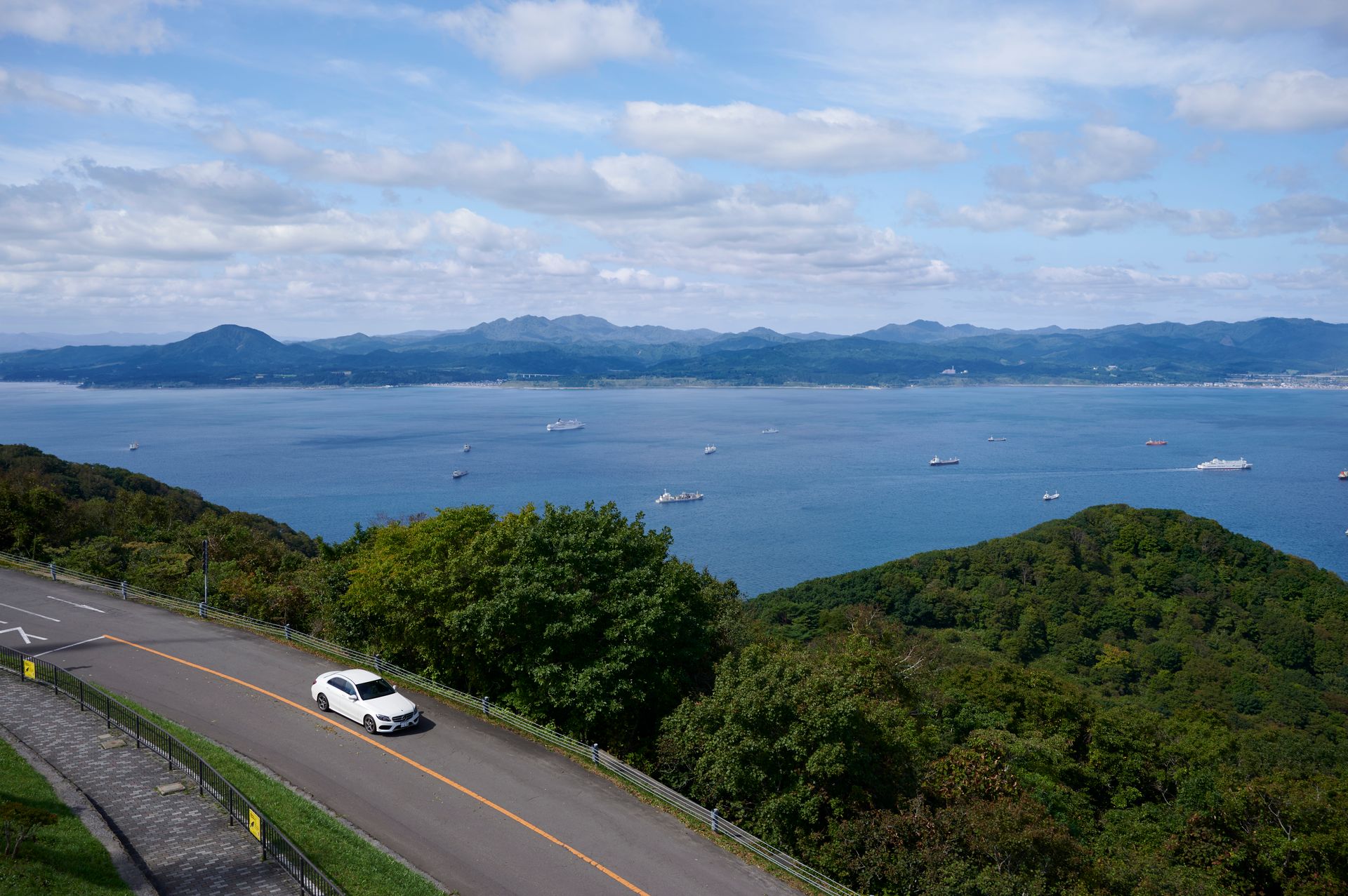 Aerial view of a car on a road overlooking coastline and sea