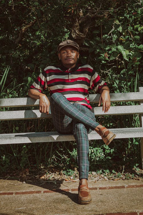 Man in Polo Shirt and Jeans Sitting on Bench