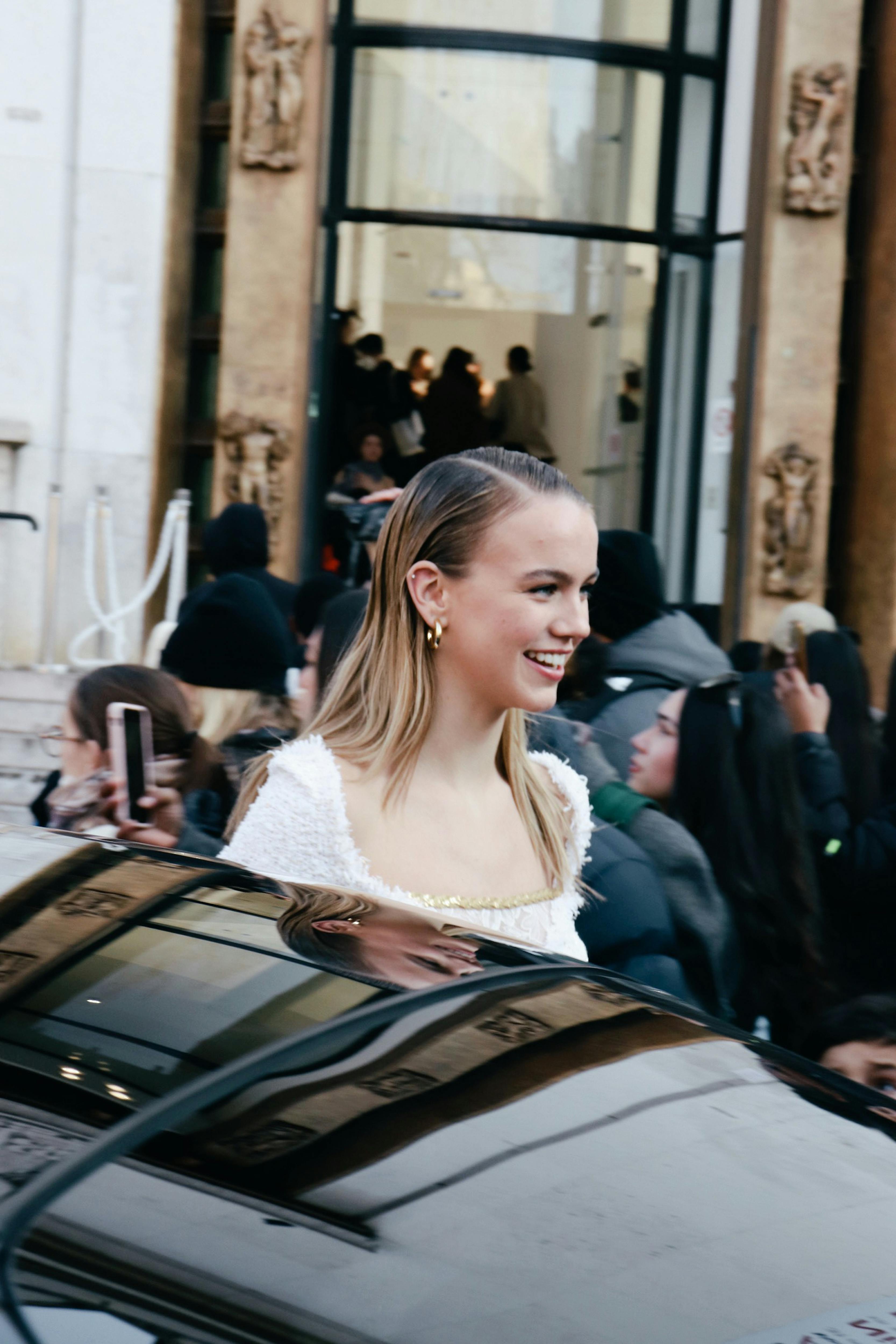 a woman in a white dress is standing outside a car