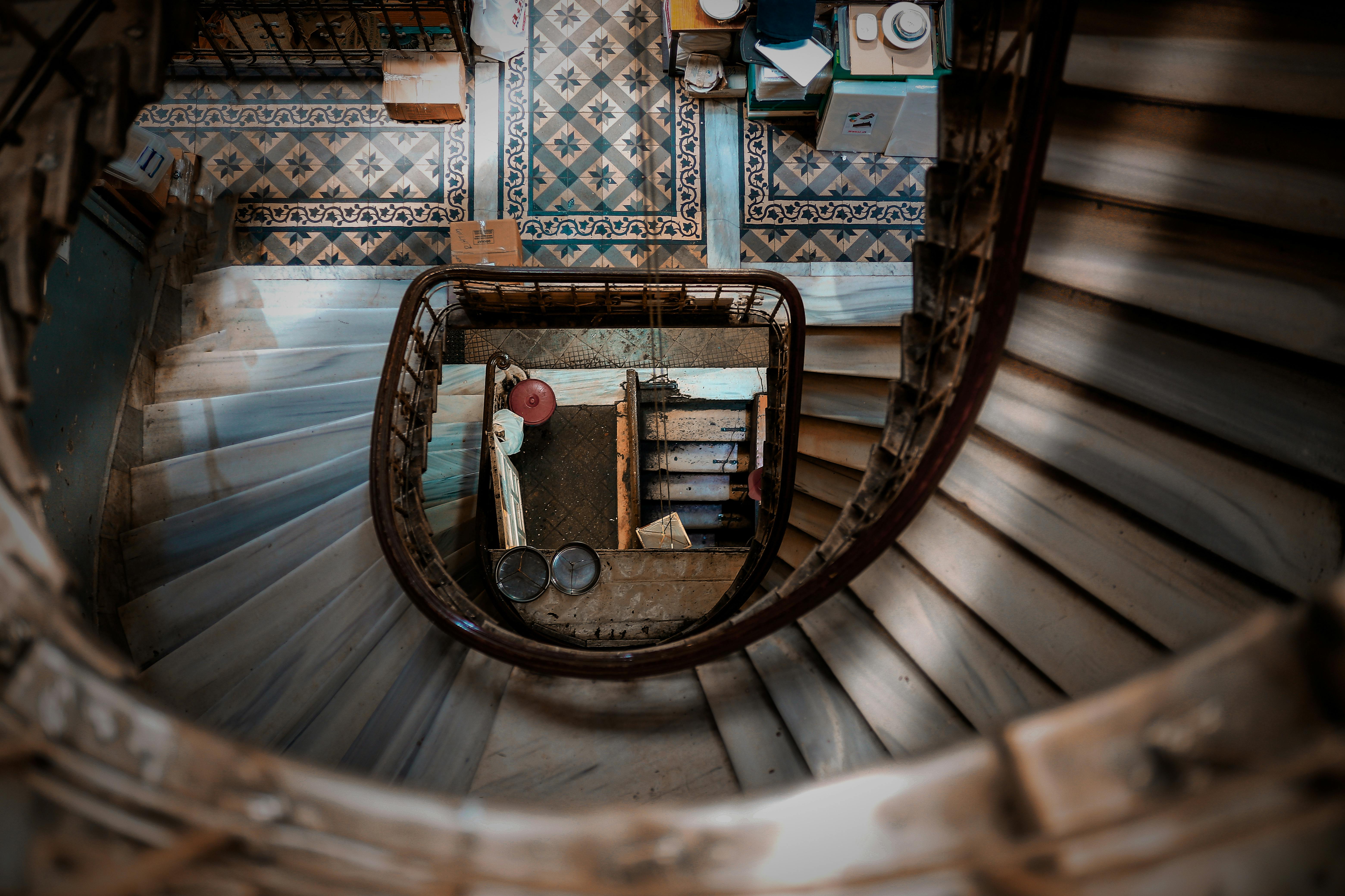 High-angle view of a vintage spiral staircase with ornate tile floor, showcasing architectural elegance.