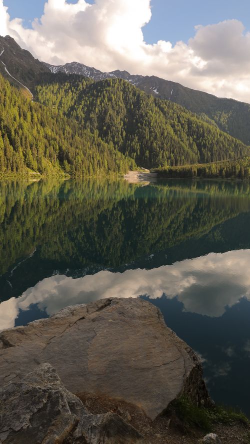 Free Stunning lake with mountain reflections and cloudy skies in a summer landscape. Stock Photo